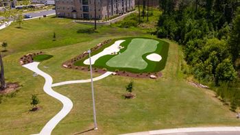 A golf course with a green and a white flag.